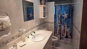 A bathroom with a white sink, mirror, and toilet. There is a shower curtain with a sea life design. - La palma Great Location Spacious Funtonal Equipied (Cancún)
