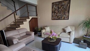 A living room with a sofa, a coffee table, a staircase, and a painting on the wall. - La palma Great Location Spacious Funtonal Equipied (Cancún)