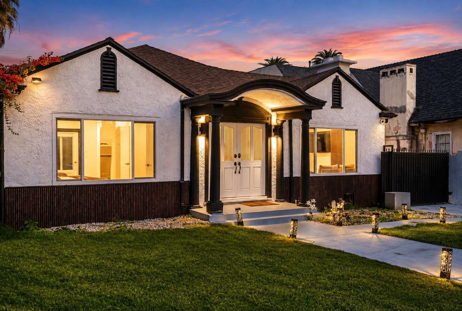 A two-story house with a white exterior, a dark roof, and a well-lit entrance.