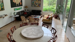 Amplia sala de estar con una mesa redonda, sillas de mimbre, un sofá y una mesa de centro.