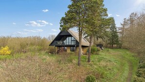 Una casa moderna con un balcone, circondata da alberi e un'area verde.