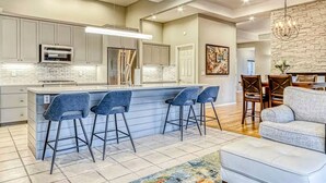 A modern kitchen with a central island, bar stools, a dining area with a table and chairs, and a living room with a sofa. - Eagle Crest Golf Resort Amenities on the 17th Tee (Redmond)