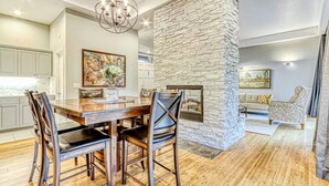 A dining area with a stone accent wall, a chandelier, and a fireplace. - Eagle Crest Golf Resort Amenities on the 17th Tee (Redmond)