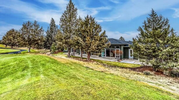 A modern house with a well-maintained lawn and tall trees. - Eagle Crest Golf Resort Amenities on the 17th Tee (Redmond)