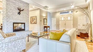 A living room with a stone fireplace, a sofa, a glass coffee table, and a floor lamp. - Eagle Crest Golf Resort Amenities on the 17th Tee (Redmond)