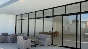 A modern outdoor patio with wicker furniture and a glass door leading to an indoor area. - Modern house with 3 bedrooms, pool, La Paz BCS (La Paz)