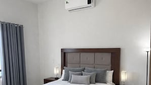 A modern bedroom with a large bed, bedside tables, a bedside lamp, and an air conditioning unit. - Modern house with 3 bedrooms, pool, La Paz BCS (La Paz)
