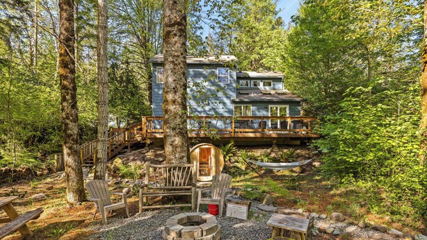 Une cabane dotée d’une terrasse, de chaises en bois, d’un foyer et d’un panneau indiquant l’interdiction de faire du feu.