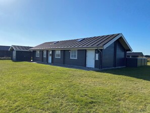 A single-story building with a dark roof, a garage, and a small attached shed. - Cozy holiday home in Vejlby Klit (Harboøre)