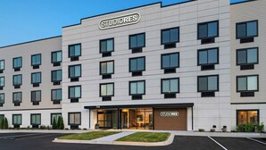 Un edificio de varios pisos con un letrero que dice 'STUDIORES', que presenta una fachada moderna con ventanas uniformemente distribuidas y un techo plano.