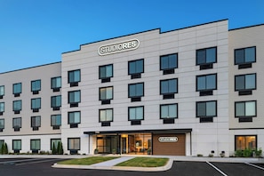 A multi-story building with a 'STUDIORES' sign, featuring a modern facade with evenly spaced windows and a flat roof.