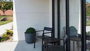 Un área de estar exterior moderna con una planta en maceta y una silla.