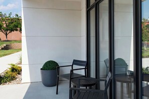 Un área de estar exterior moderna con una planta en maceta y una silla.