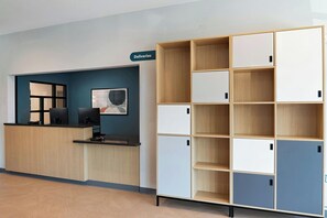A reception area with a wooden desk, a sign labeled 'Deliveries,' and a storage unit with multiple compartments.