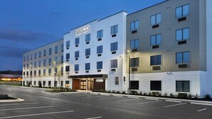 Un hotel moderno con fachada plana, múltiples ventanas y un estacionamiento.
