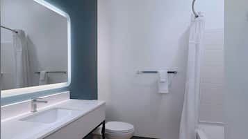 Une salle de bain moderne avec un lavabo blanc, un miroir, des toilettes et un rideau de douche.