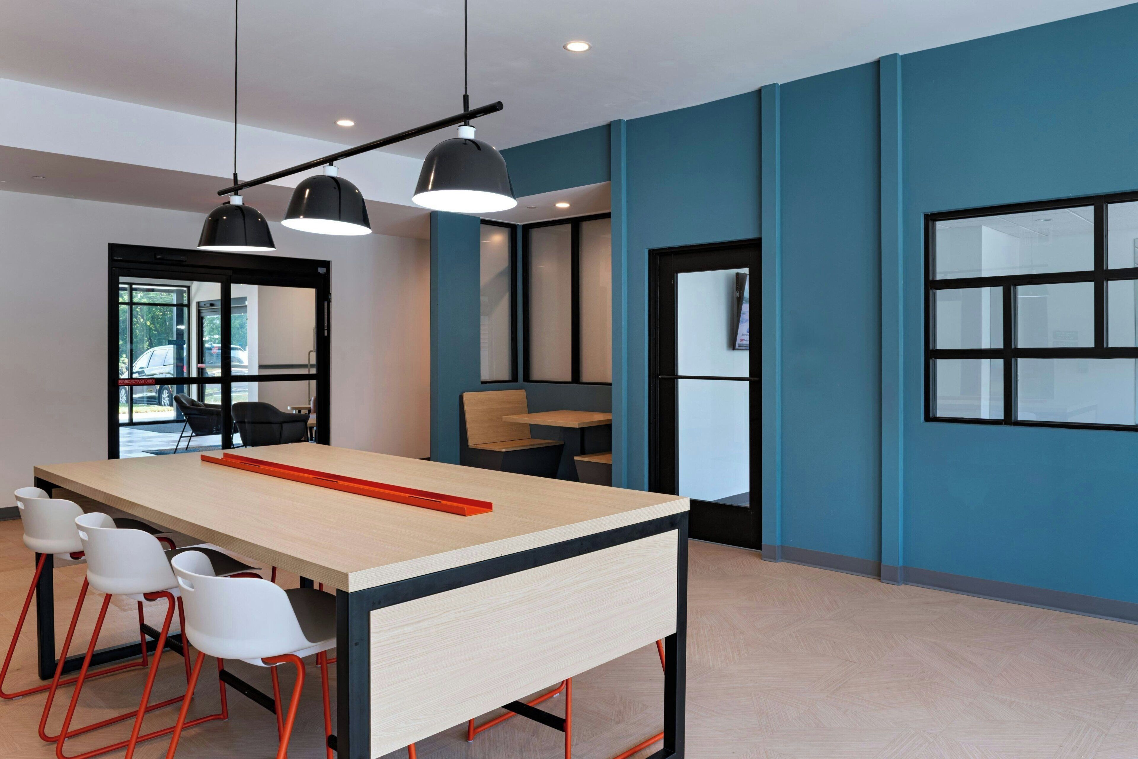A modern conference room with a long table, white chairs, and pendant lighting.