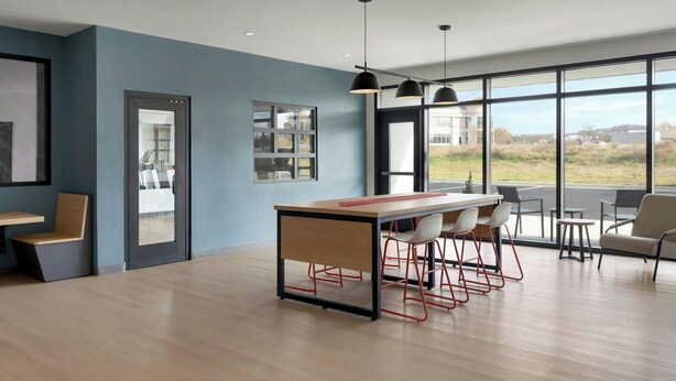 A modern kitchen with a central island, bar stools, and a large window offering a view of the outdoors. - StudioRes by Marriott Louisville East (Louisville)