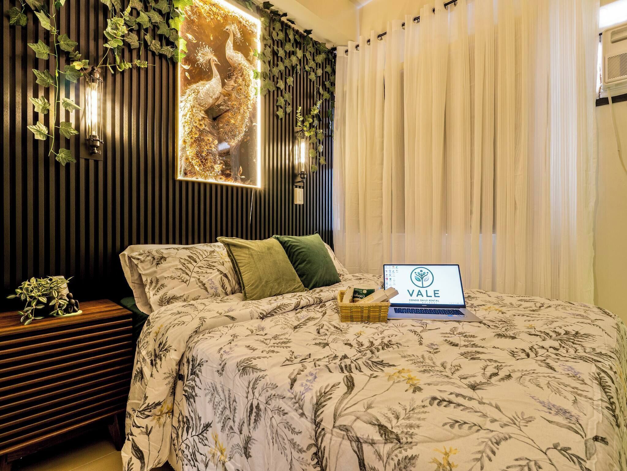 Une chambre à coucher avec un lit, un ordinateur portable, un mur décoratif et des rideaux.