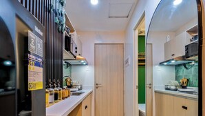Cocina pequeña con refrigerador, un lavamanos y una puerta que da a otra habitación.