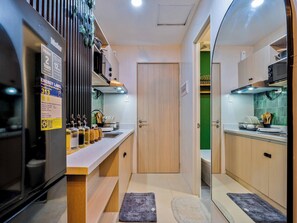 A compact kitchen with a refrigerator, a sink, and a door leading to another room. - Forest-themed Cozy Studio Near IT Park Cebu (Cebu City)