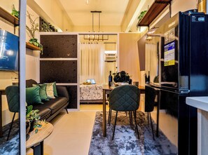 A modern living room with a sofa, coffee table, and a dining area with chairs and a table. - Forest-themed Cozy Studio Near IT Park Cebu (Cebu City)