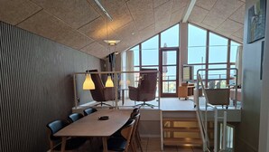 A modern meeting room with a large table, chairs, and a view through large windows. - Holiday home near forest and beach (Egernsund)