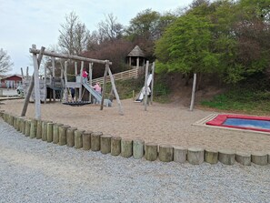 Ein Spielplatz mit Schaukeln, Rutschen und einer kleinen Schutzhütte.