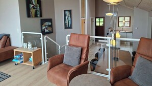 A spacious living area with a high ceiling, a glass railing, and a modern pendant light. - Holiday home near forest and beach (Egernsund)