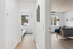 A hallway leading to a bedroom with a bed, a window, and a grey sofa in the living area. - Active holiday in large home with garden (Vig)