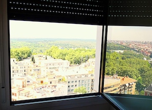 Blick aus einem Fenster auf eine Stadtansicht mit Gebäuden und Grünflächen.