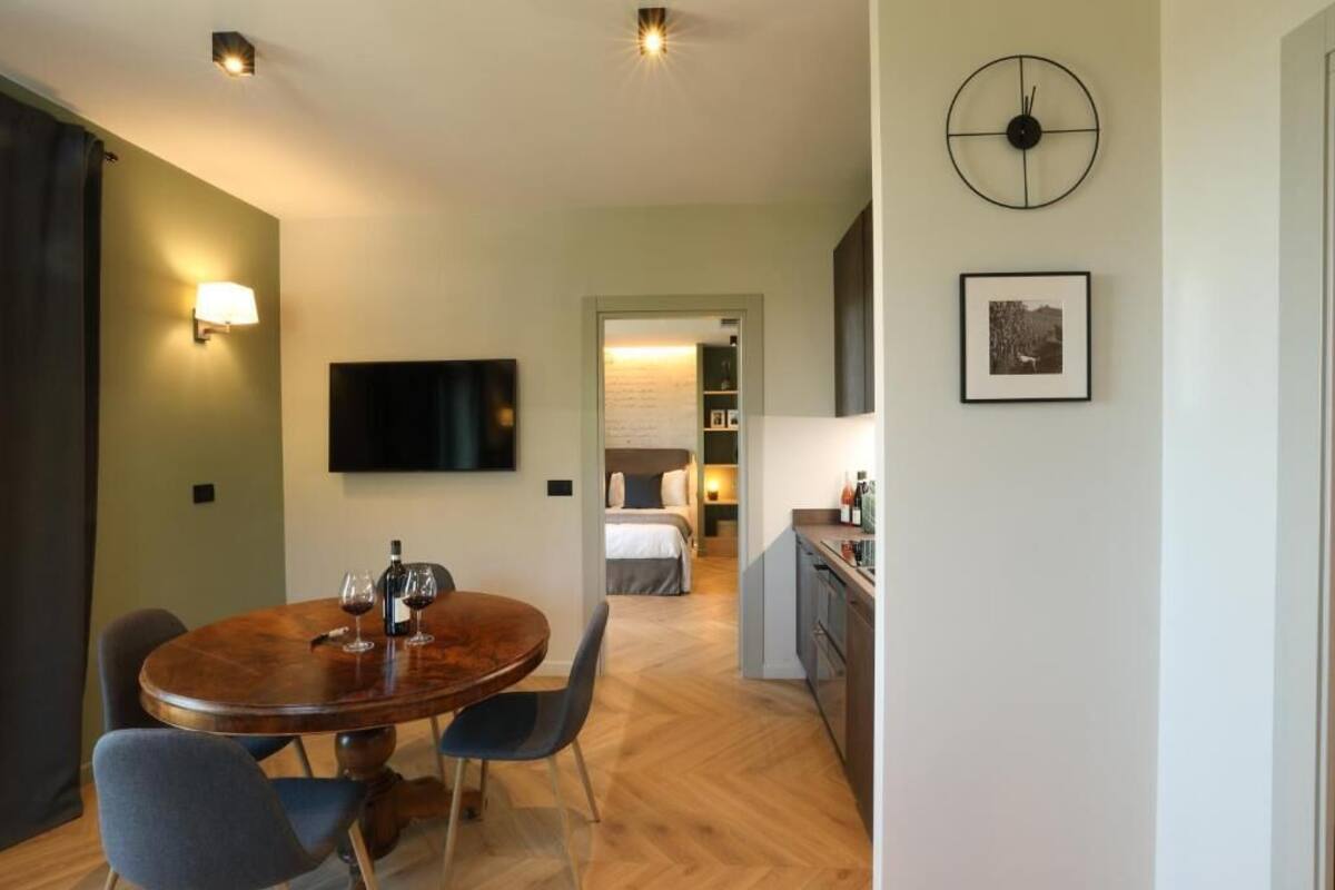 Une pièce moderne avec une table de salle à manger ronde, des chaises, un téléviseur à écran plat, une horloge et un tableau encadré au mur.