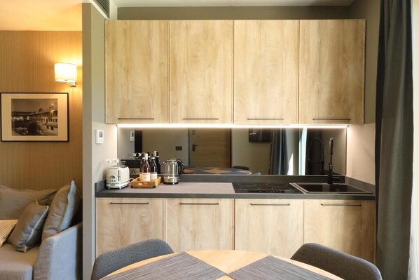 A compact kitchen with wooden cabinets, a dining table, and a coffee maker.