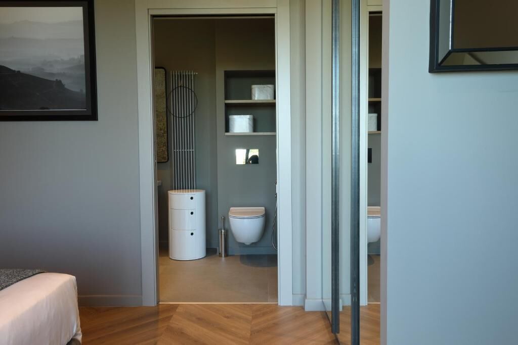 A modern bathroom with a toilet, sink, and storage shelves.