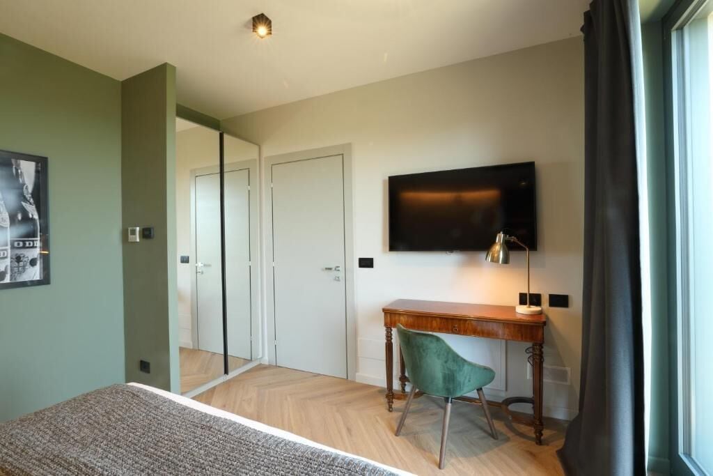 Ein Schlafzimmer mit Bett, Schreibtisch, Sessel, Fernseher und Kleiderschrank.