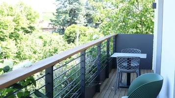 A balcony with a wooden railing, a table, and a chair.