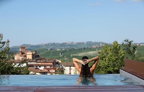 A person relaxing in a pool with a view of a town and hills.