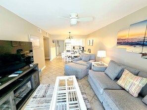 A living room with a television, sofa, and a dining area in the background. - Perdido Dunes 27 Beach Side Orange Beach (Orange Beach)