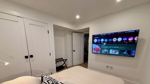 A bedroom with a bed, a TV mounted on the wall, a wardrobe, and a small table with a chair. - Light-Filled Lower Suite · Brand New · Private · 5 Mins to Metro · Parking (Washington)