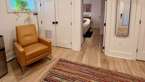 A modern interior with a leather chair, a colorful rug, and a bedroom with a bed and a mirror. - Light-Filled Lower Suite · Brand New · Private · 5 Mins to Metro · Parking (Washington)