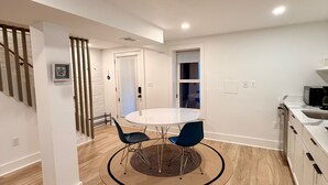 A modern kitchen with white cabinetry, a round dining table with two chairs, and a wooden floor. - Light-Filled Lower Suite · Brand New · Private · 5 Mins to Metro · Parking (Washington)
