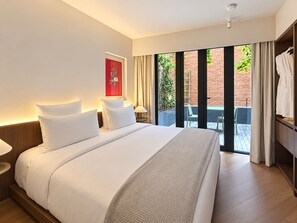 A hotel room with a large bed, a red wall decoration, and a view of a brick building through a glass door. - EMA Condesa (Mexico City)