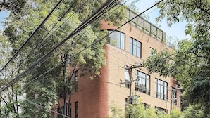 A multi-story building with a brick facade, large windows, and a parking sign. - EMA Condesa (Mexico City)