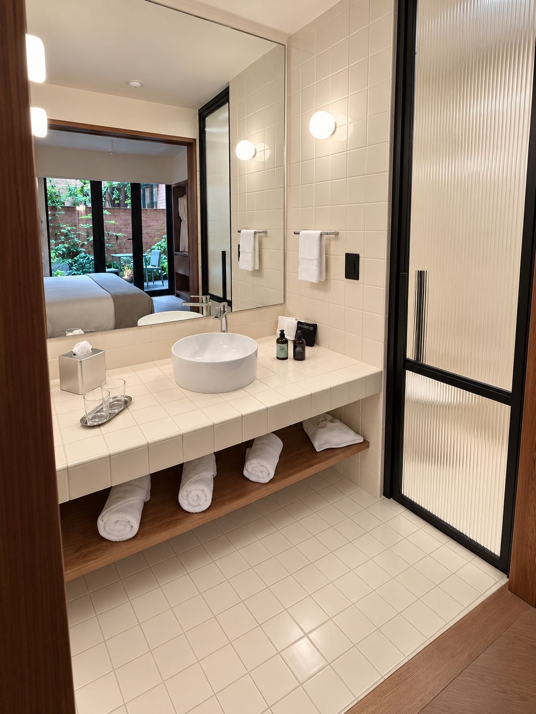 Un baño moderno con un espejo grande, un lavabo redondo y una zona de ducha.