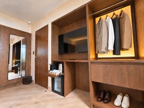 A modern walk-in closet with a flat-screen TV, a mirror, and shelves for shoes and clothes. - EMA Condesa (Mexico City)