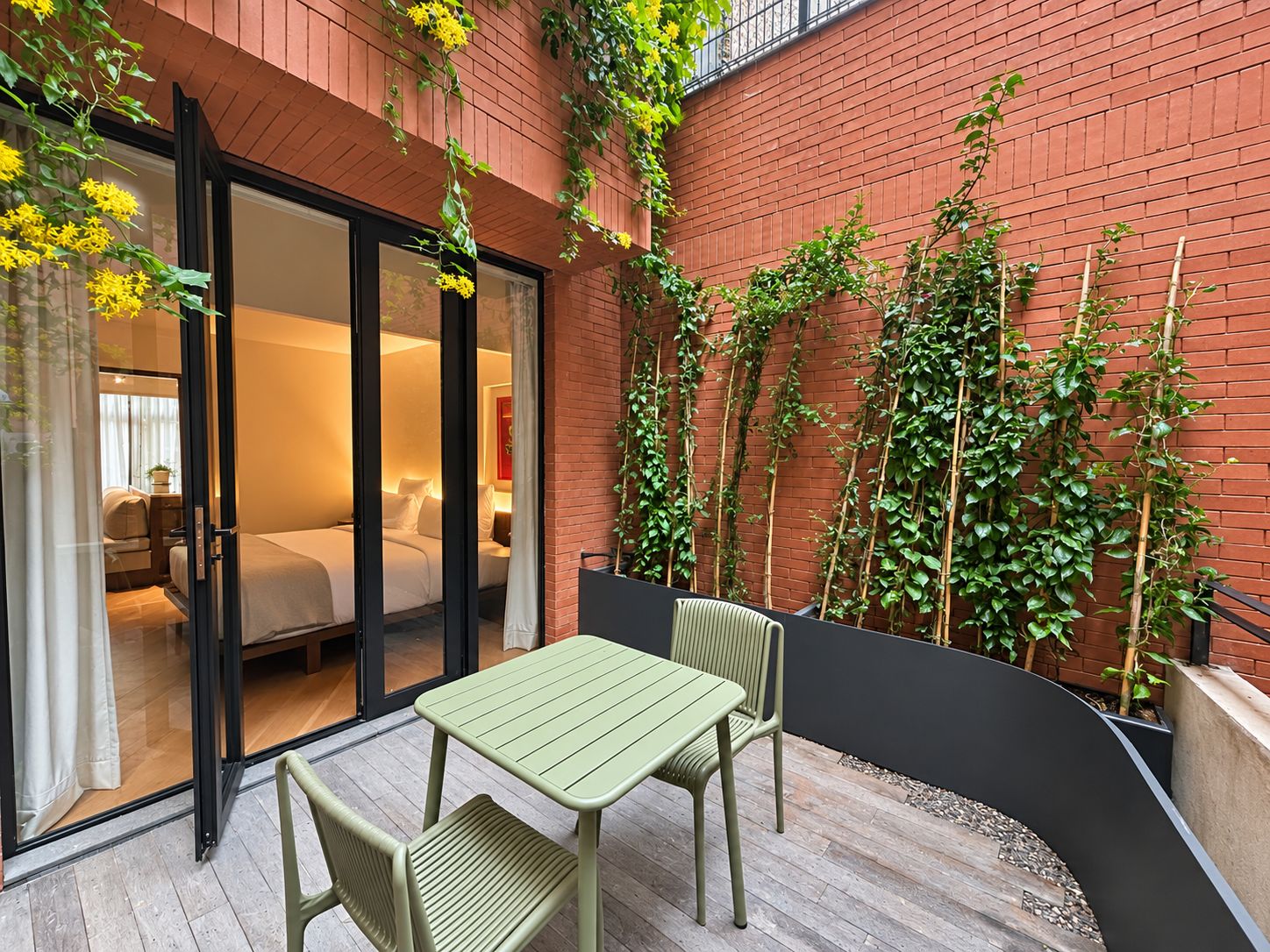 Een hotelkamer met een schuifglazen deur die uitkomt op een balkon met een tafel en stoelen.