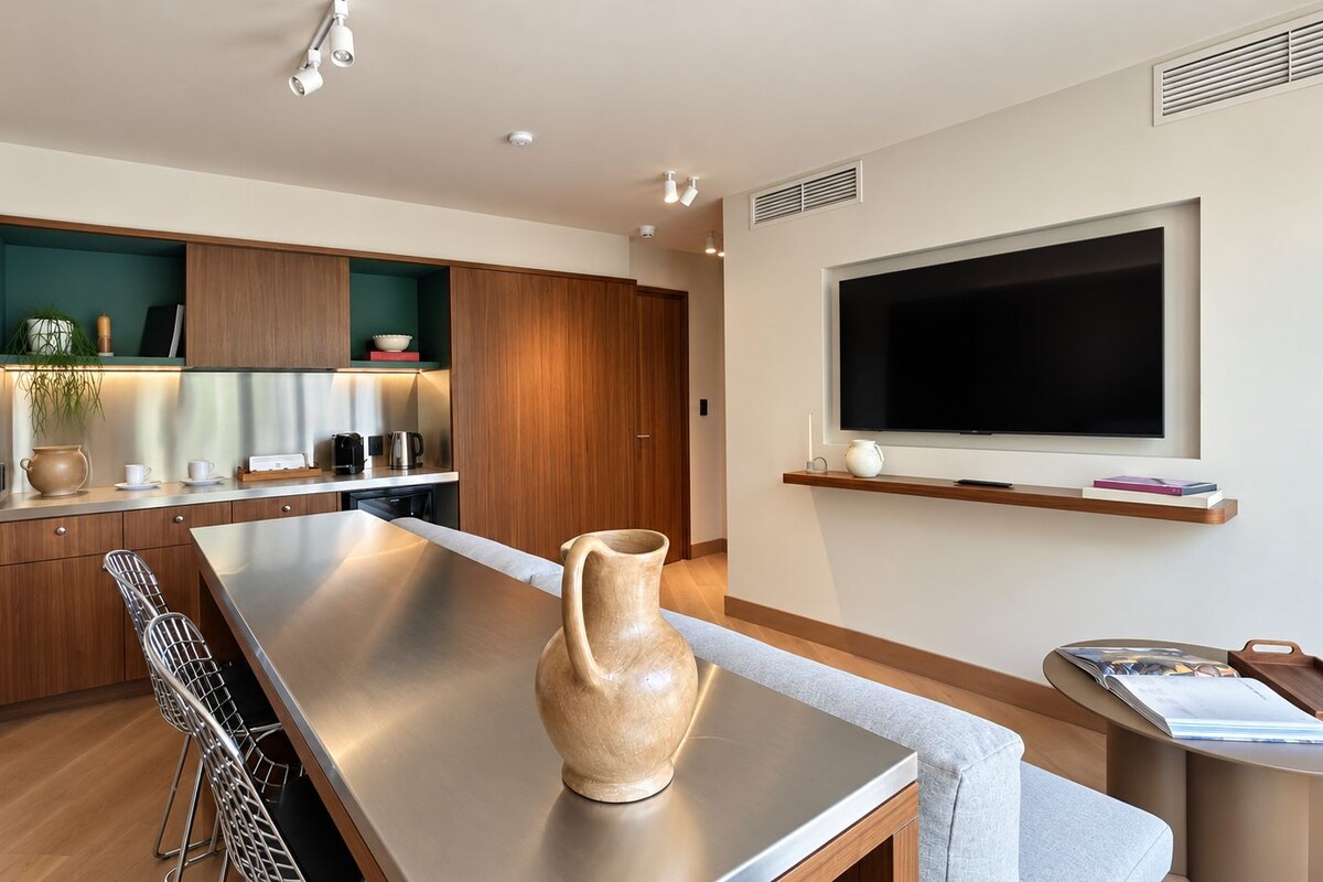 A modern kitchen with a long countertop, a wooden cabinet, and a built-in TV above it.