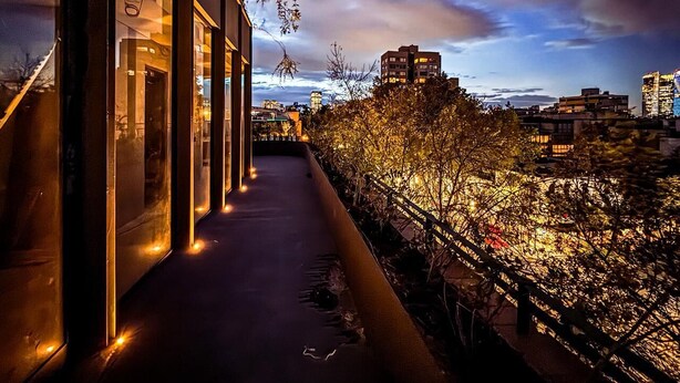 A modern building with large windows and a balcony overlooking a cityscape at dusk. - EMA Condesa (Mexico City)