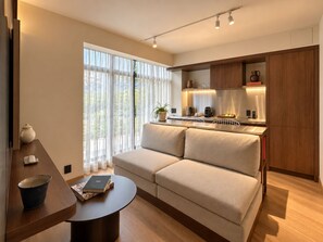 Un salon moderne comprenant un canapé, une table basse et un coin cuisine avec un plan de travail et des placards.