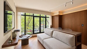 A modern living room with a sofa, a coffee table, and a TV mounted on the wall. - EMA Condesa (Mexico City)